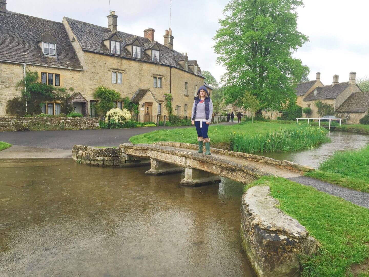 a bridge over a stream in Lower Slaughter, with yellow stone houses behind. 