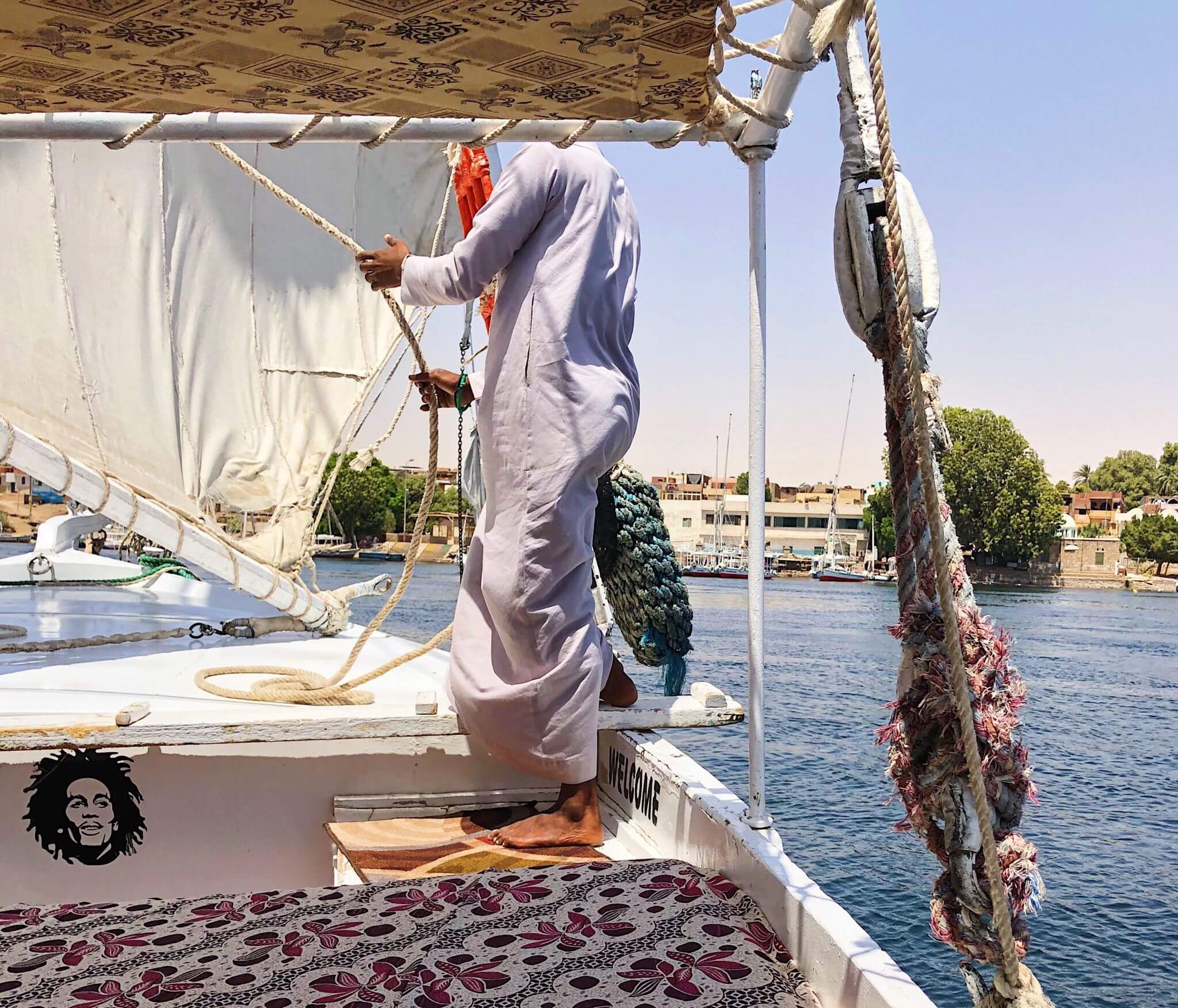 A nubian sailing the felucca against the blue Nile with the canopy