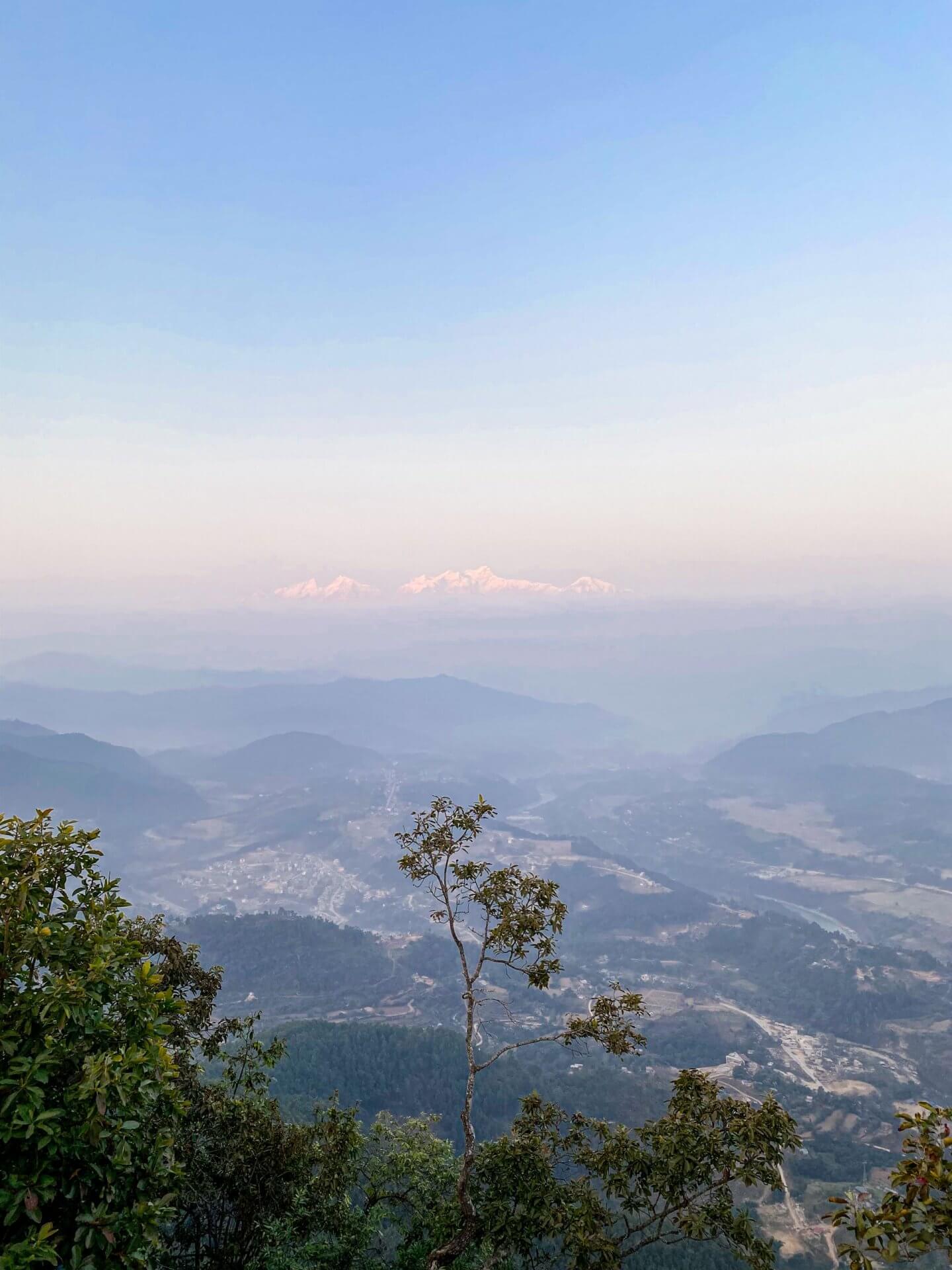image of the Himalayas peaking over the clouds from the Tundikhel viewpoint in Bandipur Nepal