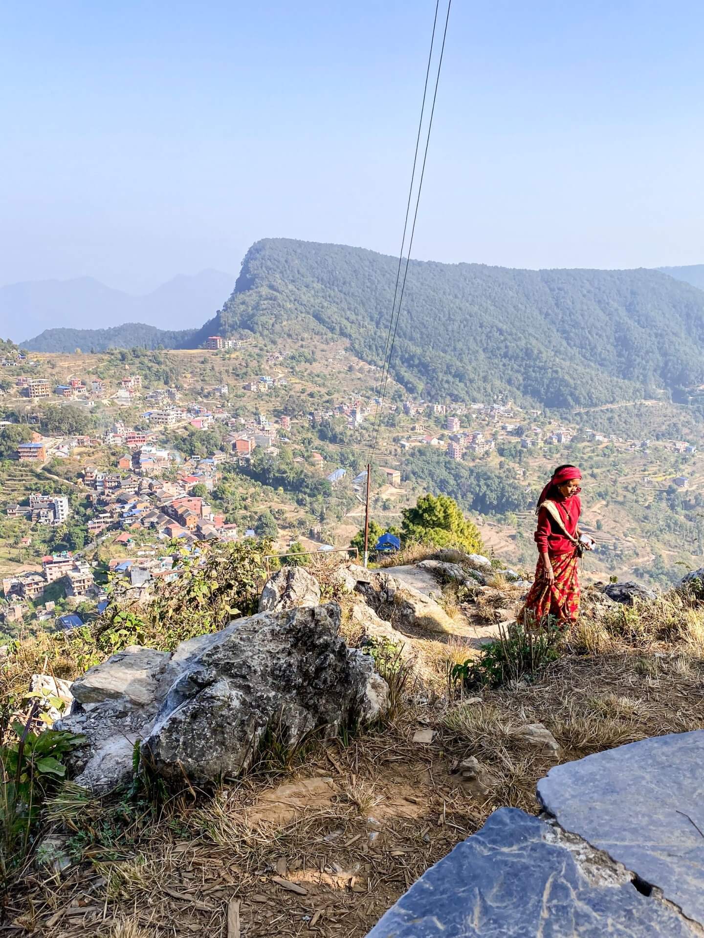 image of a woman dressed in Nepali dress walking up the steps to Thani Mai in Bandipur Nepal