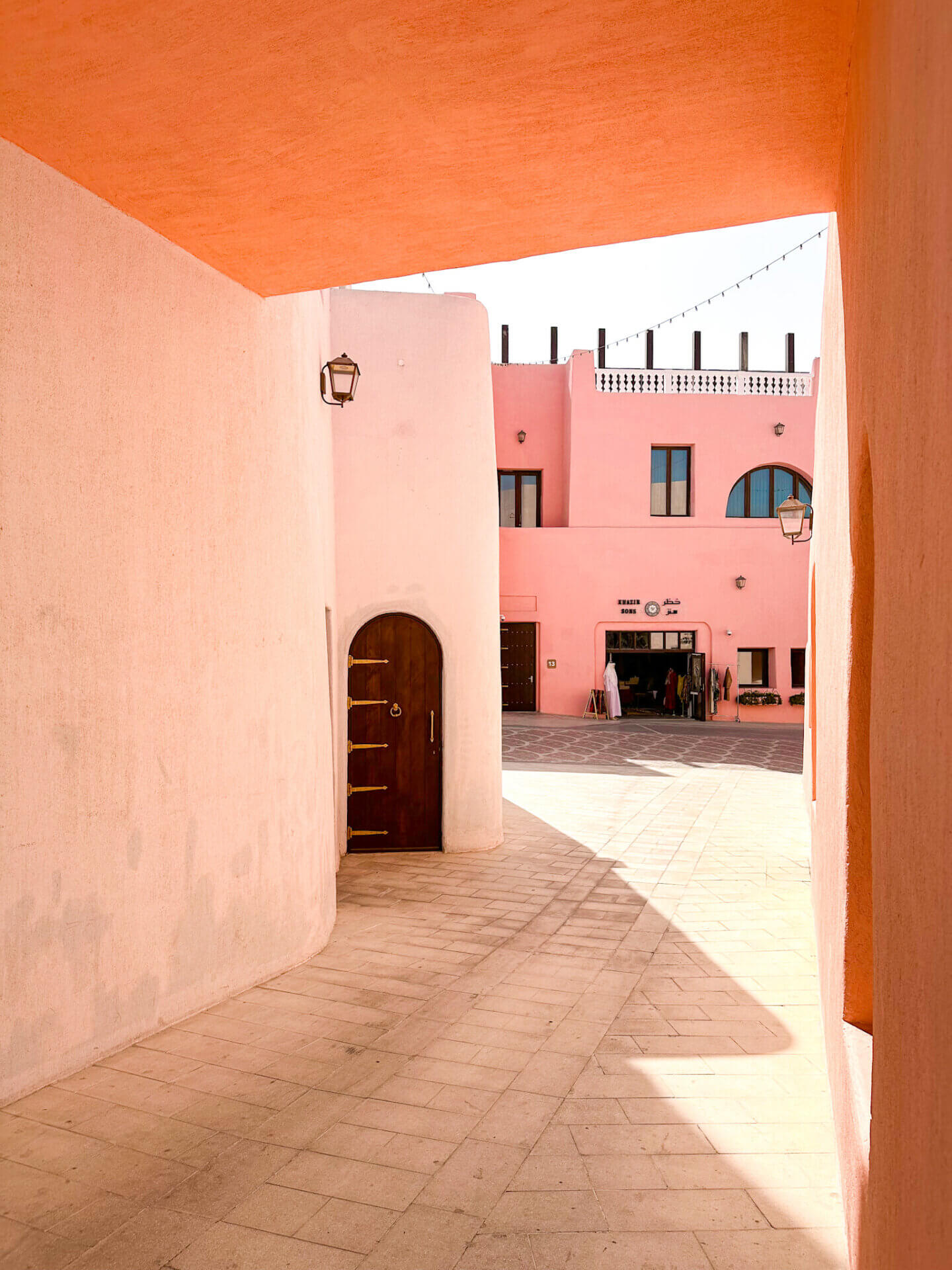 A pink building in the Mina District of Doha is visible through a peach arch