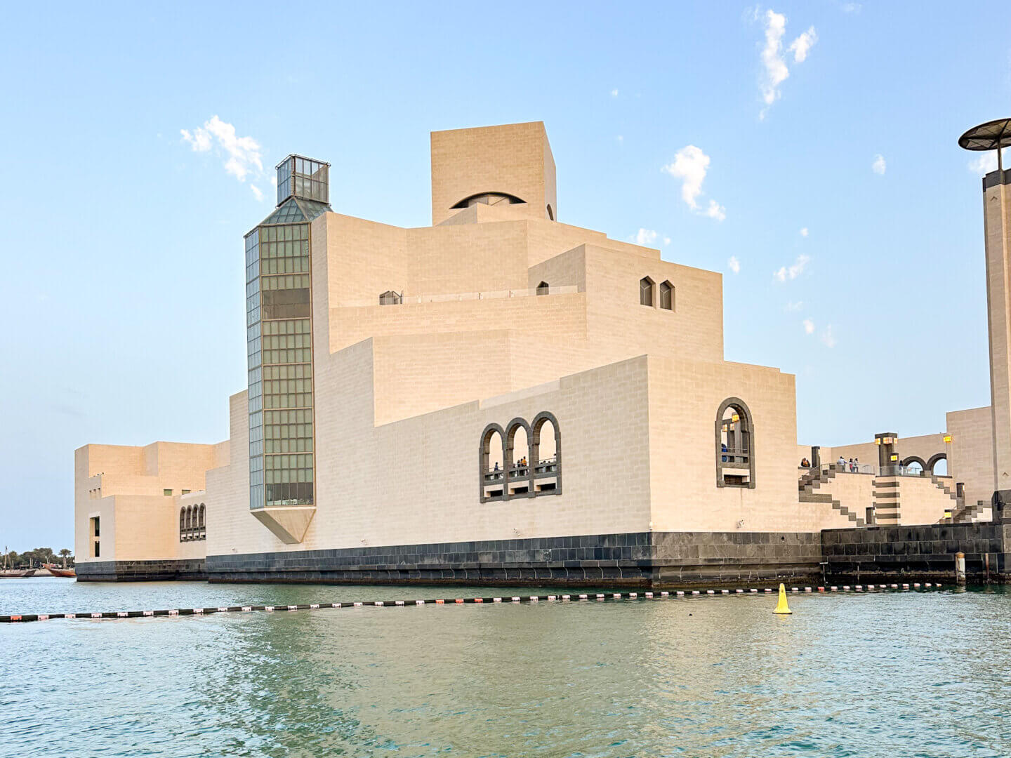 Sharp cubic lines forming the white boxesque Museum of Islamic Art. The picture is taken from the water, with the sea in front.