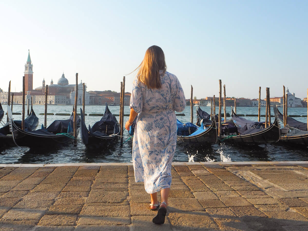 Charlie walking away from the camera overlooking a line of gondalas in Venice