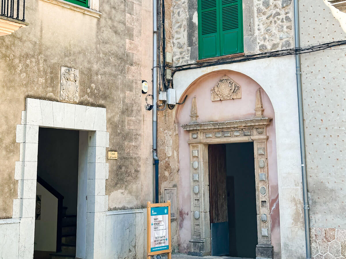 Exterior view of the Valldemossa Chopin Museum entrance, showcasing classic Spanish architecture and green shutters.
