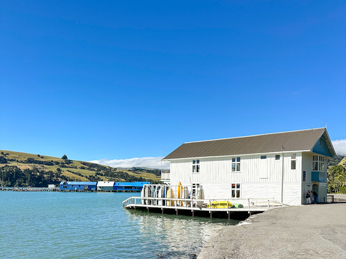 Historic white wooden boat shed on the picturesque waterfront of Akaroa, a charming French settlement in the Banks Peninsula, South Island, New Zealand