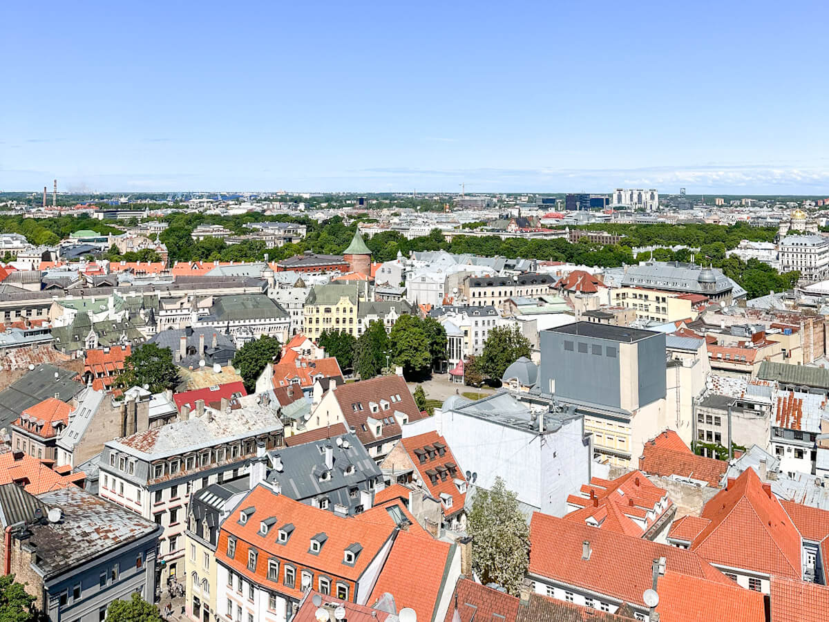 What to do in Riga: A sweeping panoramic view of Riga's red-tiled Old Town rooftops and the wider modern city skyline under a clear blue sky.