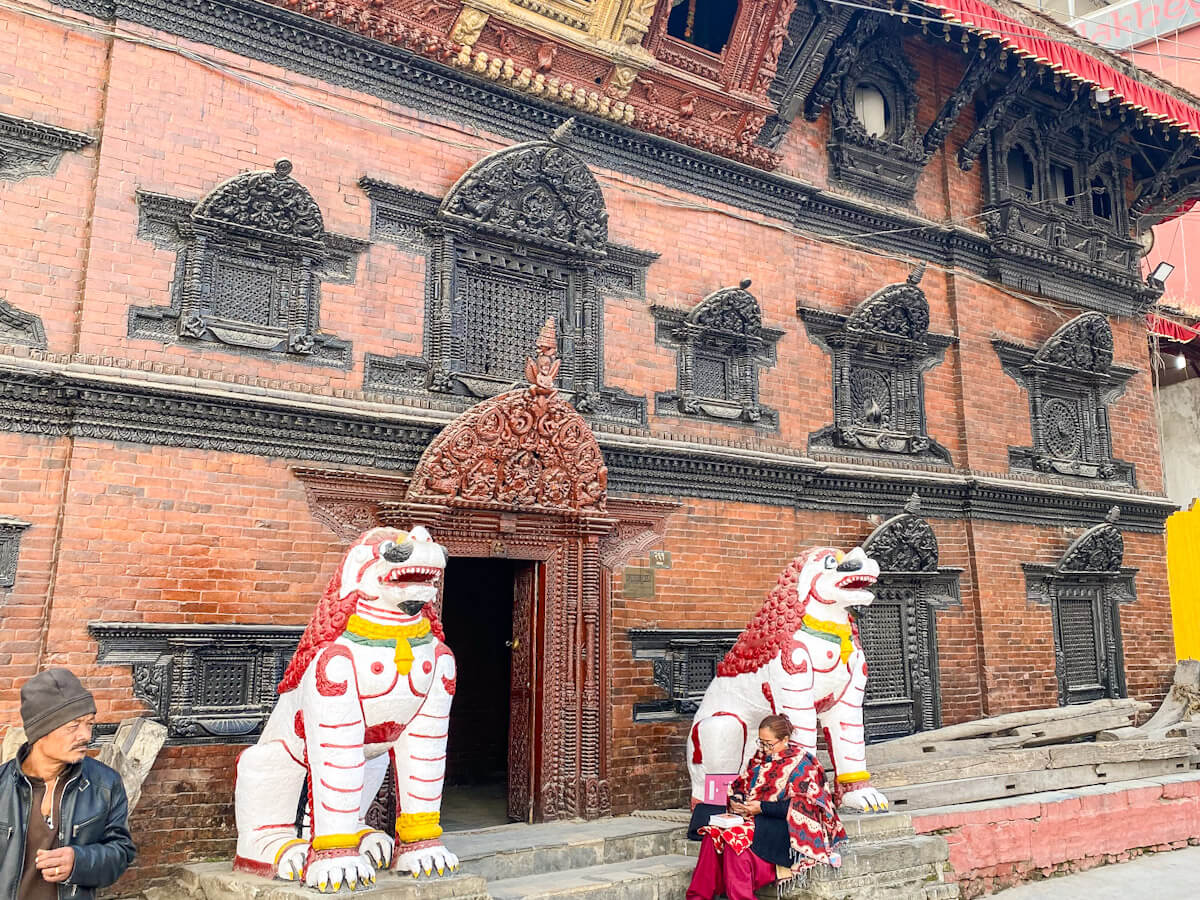 The entrance to the Kumari Chhen, the official residence of the Living Goddess (Kumari Devi) in Kathmandu, guarded by two brightly painted stone lion statues. Visiting the Living Goddess's house is one of the most culturally unique and fascinating places to visit in Kathmandu.
