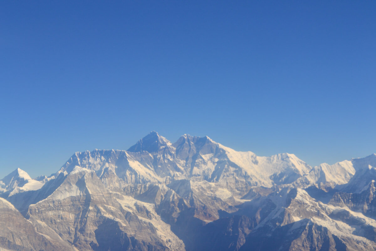 Mount Everest and the Himalayan mountain range seen from an airplane window, showcasing the snow-capped peaks and vast blue sky, a truly breathtaking sight near the essential places to visit in Kathmandu.