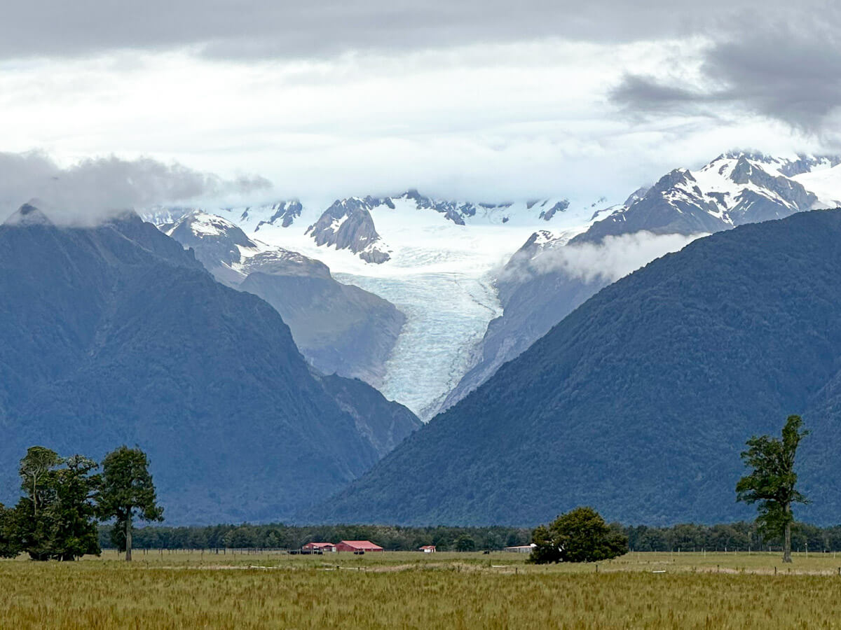 View of Fox Glacier flowing between snow-capped mountains on New Zealand’s West Coast