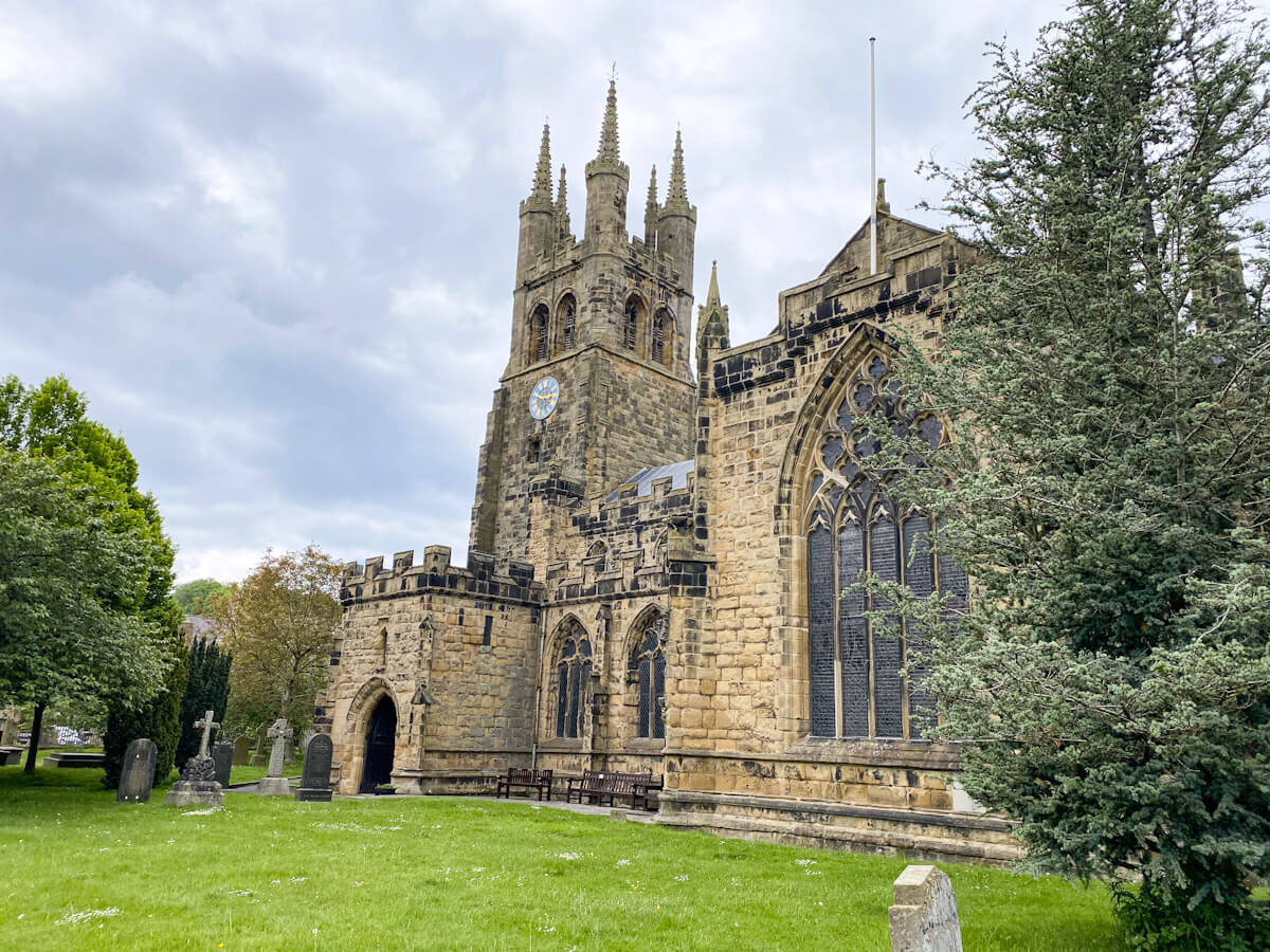 The impressive Gothic architecture of the "Cathedral of the Peak" in Tideswell, one of the best villages in the Peak District, showing its ornate stone towers and stained glass windows.
