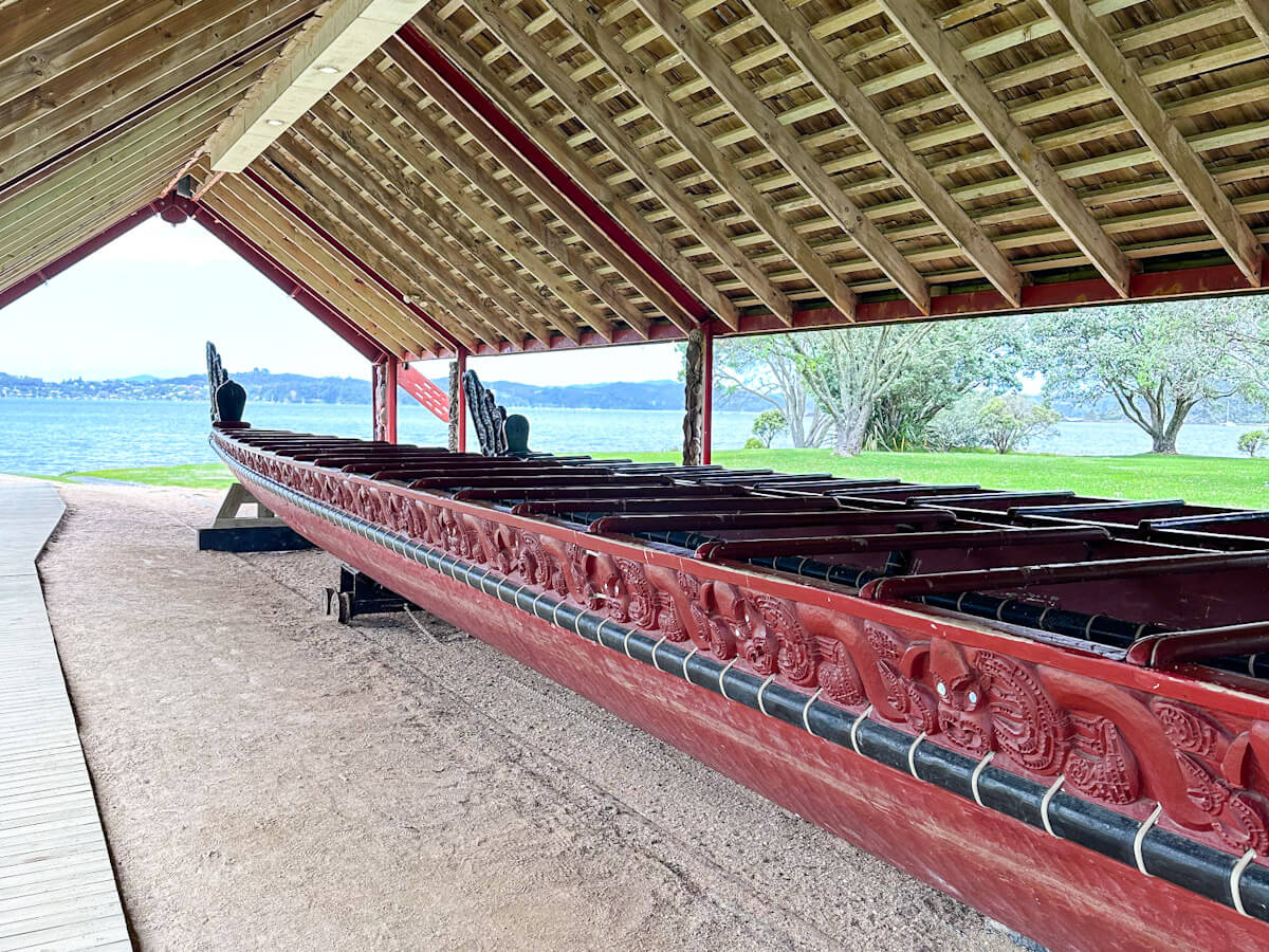 An intricately carved Mฤori waka (war canoe) under a traditional shelter at the Waitangi Treaty Grounds, a top cultural activity for what to do in Paihia.