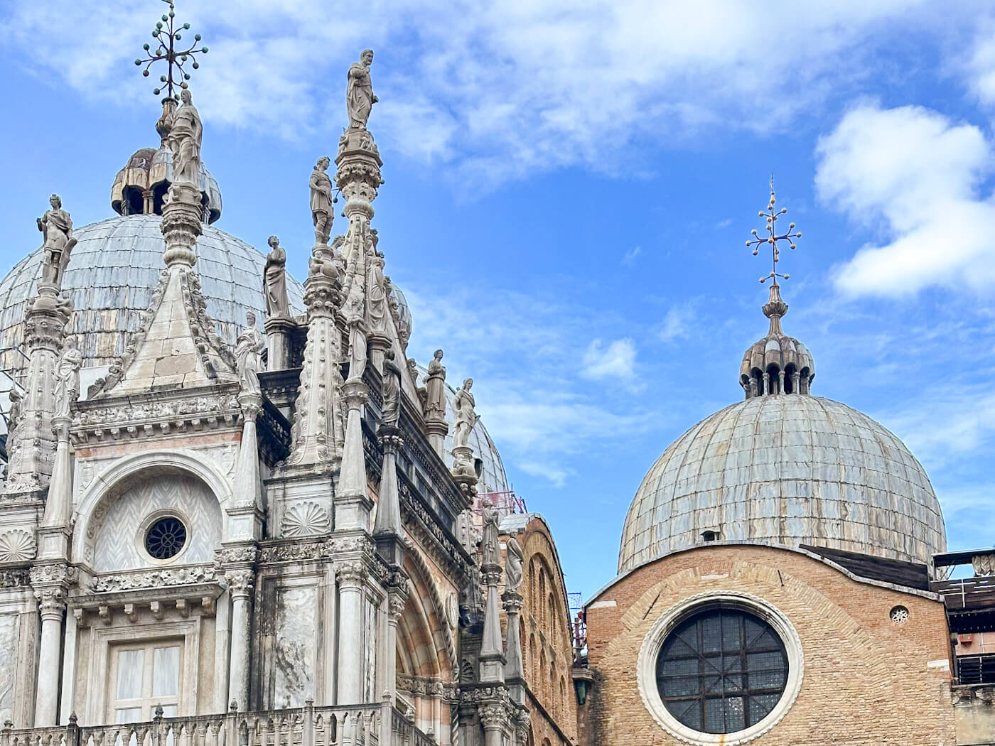A detailed view of the white marble statues and domes of St. Mark's Basilica against a bright blue sky, showcasing the city's Byzantine architecture in Venice in the winter