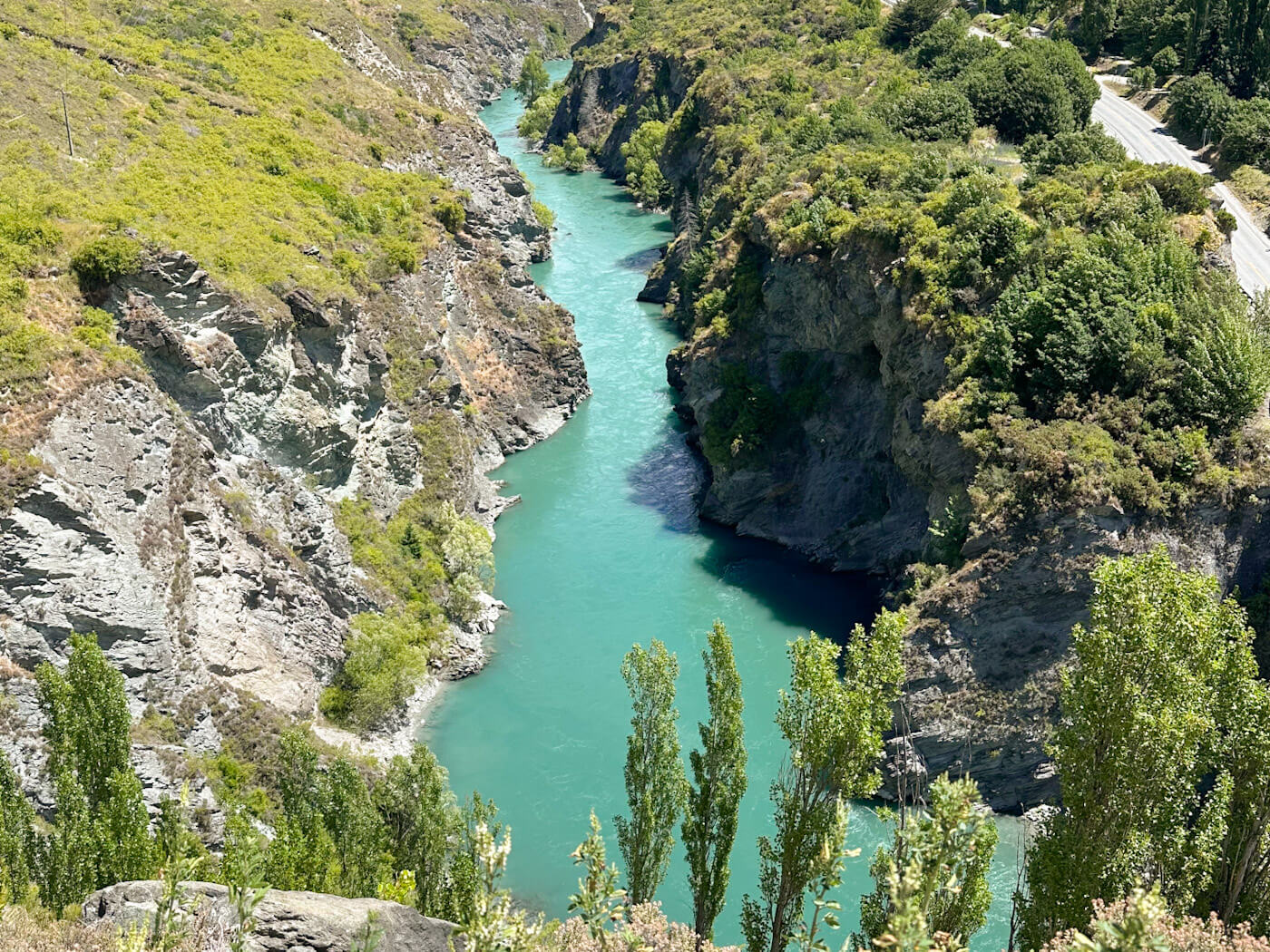 A high-angle view looking down at the bright turquoise waters of the Kawarau River as it snakes through a steep rocky gorge in Queenstown, New Zealandโthe filming site for the Pillars of the Kings, or the Argonath, in The Lord of the Rings