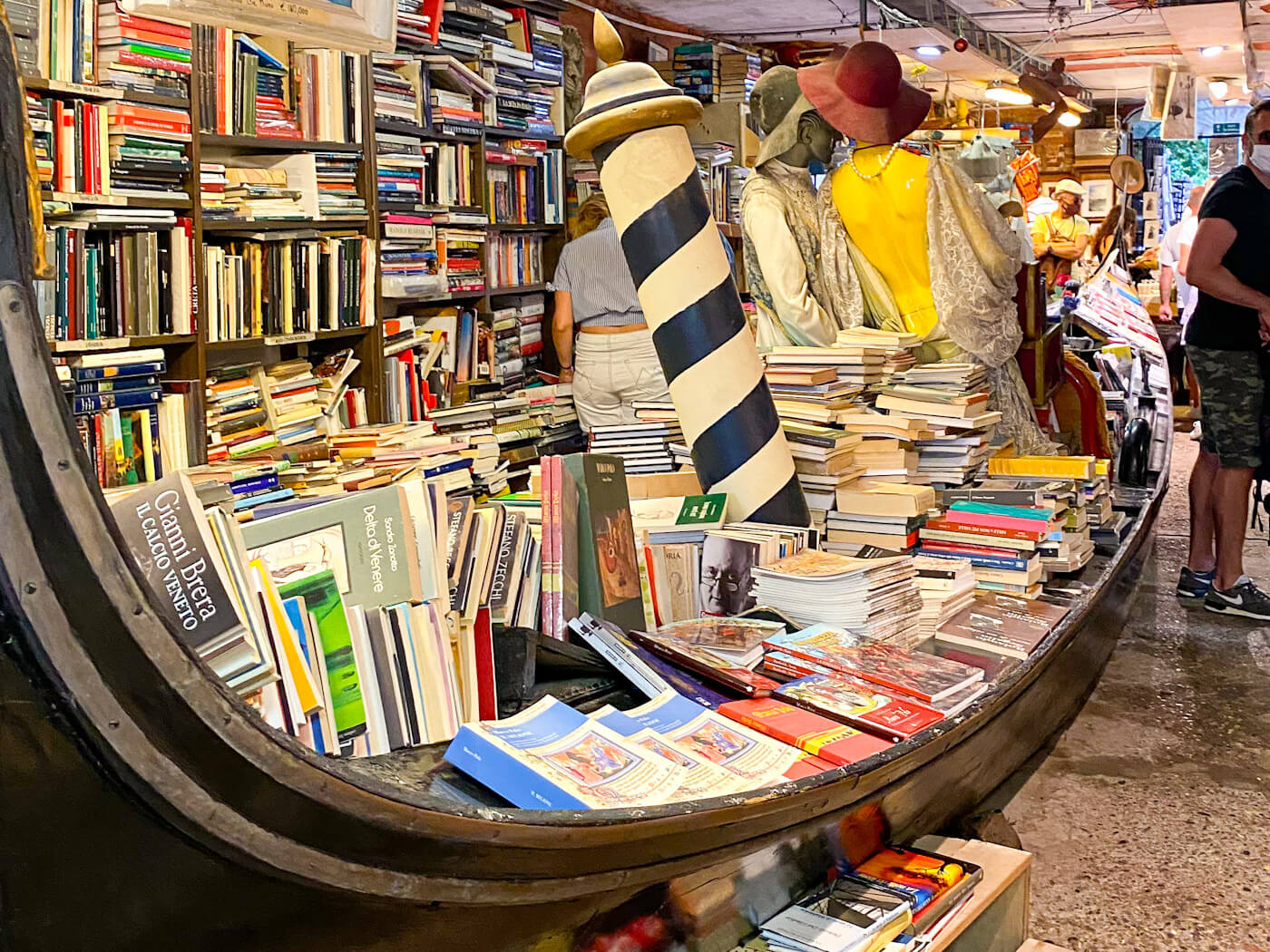 A full-sized gondola used as a bookshelf inside the famous Libreria Acqua Alta bookstore, filled with stacks of books to stay dry during high tide in Venice in the winter.