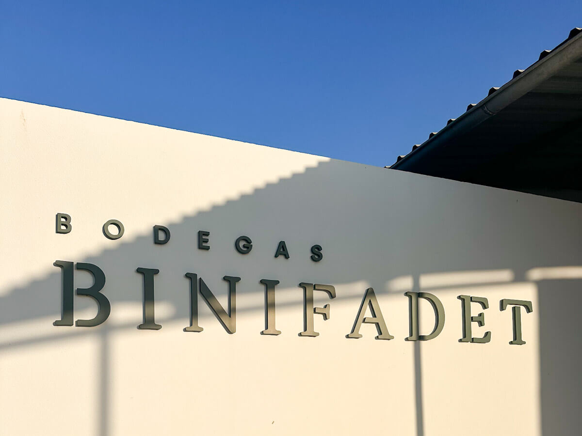 The sleek white exterior wall of Bodegas Binifadet under a bright blue sky, one of the best things to do in Menorca for wine lovers