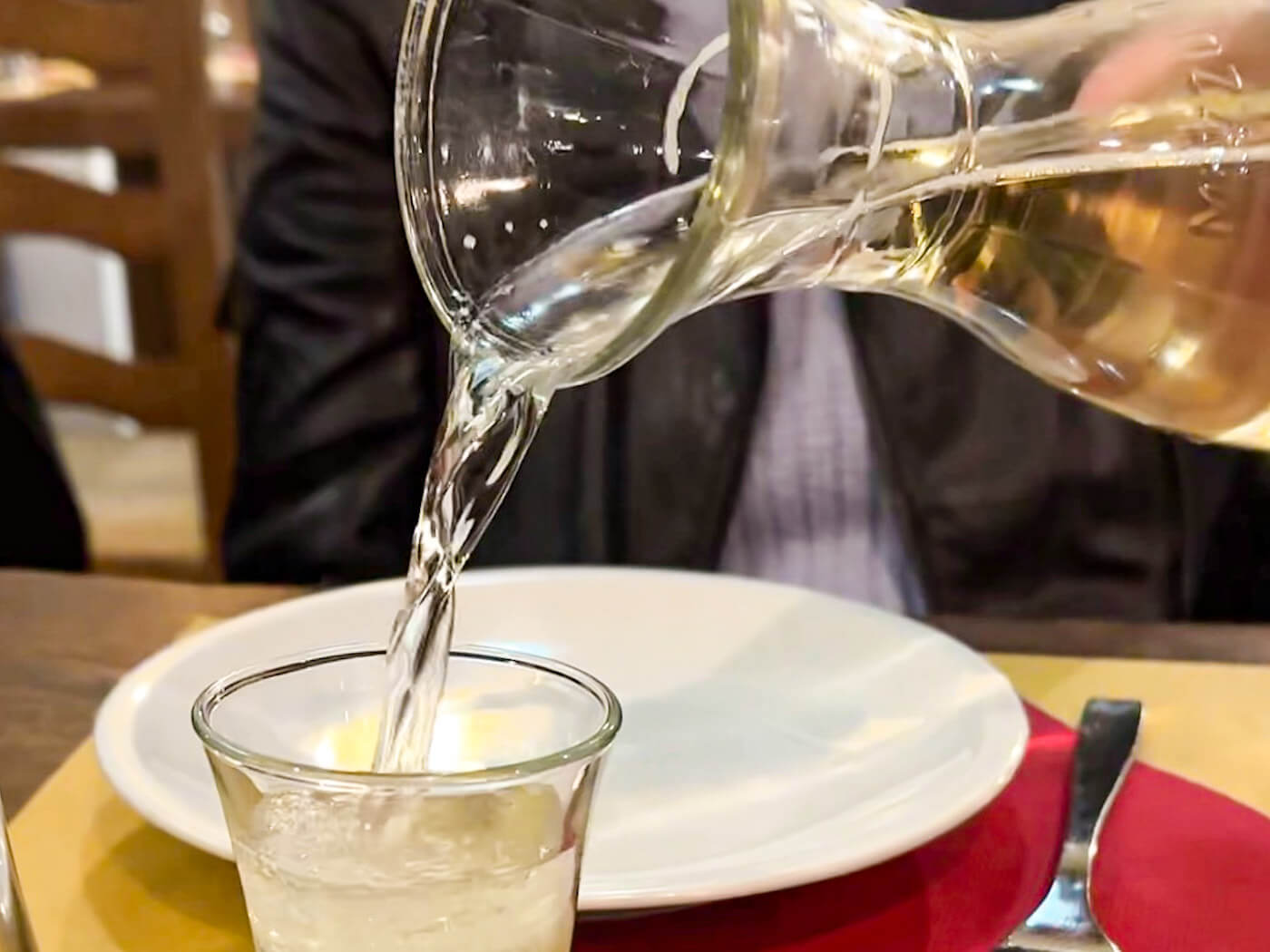A small glass of ombra being poured from a carafe at Antica Osteria Ruga Rialto — one of the best places for where to eat in Venice like a local.