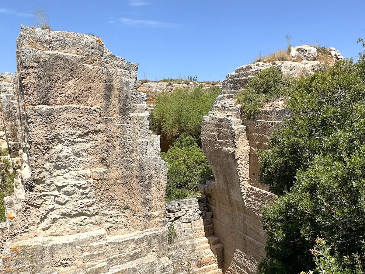 Close-up of the weathered marรฉs stone at the Lithica quarry, showing narrow stairs carved directly into the rock face leading through a narrow passage.