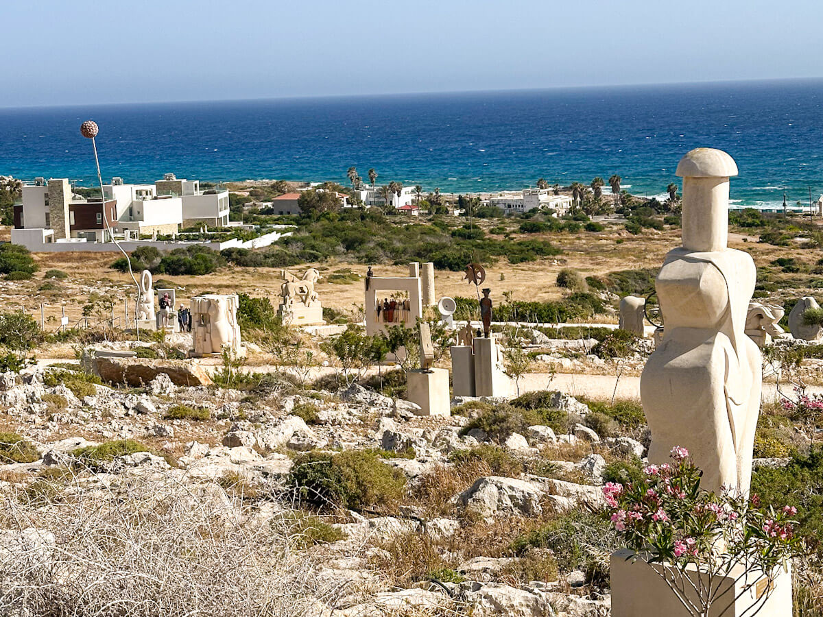 An outdoor art exhibition at the Ayia Napa Sculpture Park on a rocky hillside overlooking the deep blue Mediterranean Sea, a popular cultural attraction to see when you visit Ayia Napa.