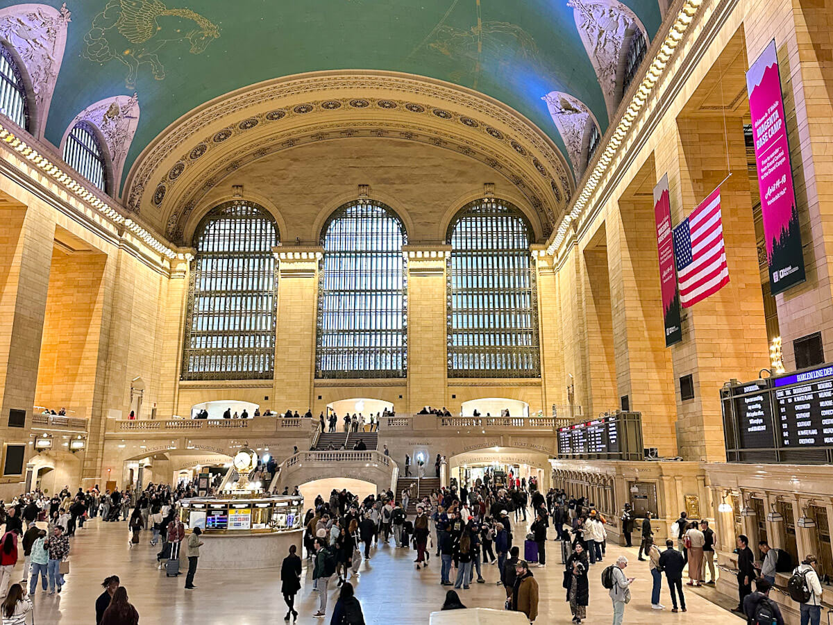 A wide-angle interior view of the bustling Main Concourse in Grand Central Terminal, featuring its massive arched windows, ornate ceiling, and crowds of people moving across the floor during 5 days in New York