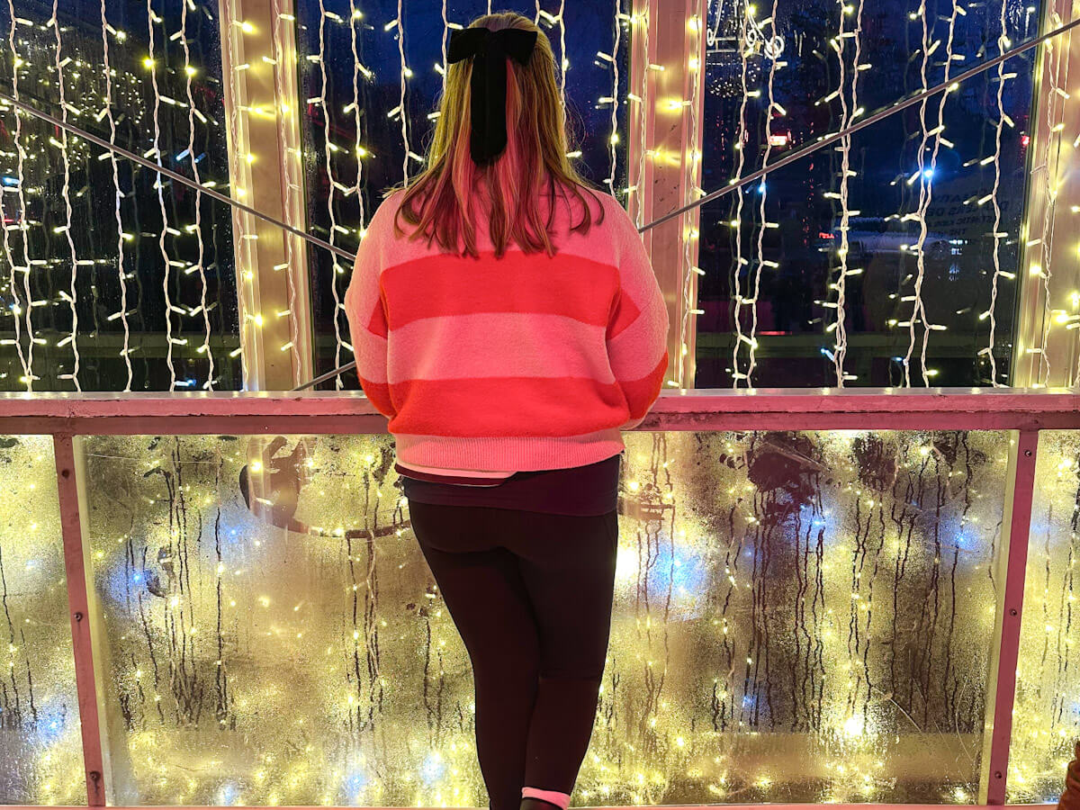 Charlie looking out through glowing fairy lights at the ice rink in Koning Albert I Park during Bruges at Christmas