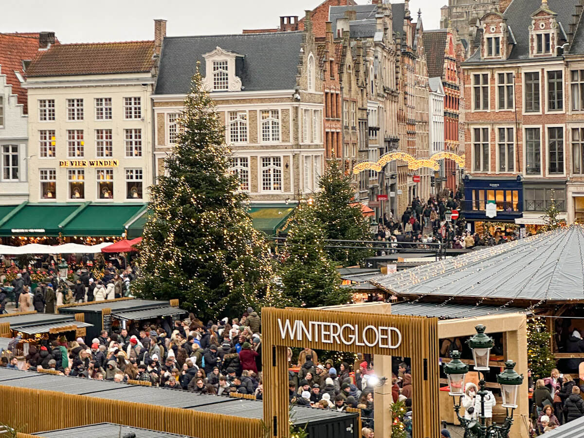 High-angle view of the bustling Markt Christmas market stalls and giant tree during Bruges at Christmas