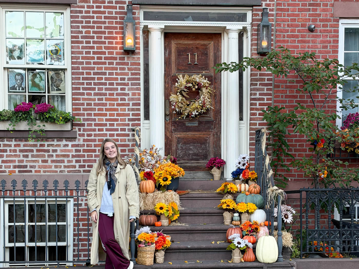 Charlie standing by a brownstone stoop decorated with sunflowers, pumpkins, autumn wreaths, and fall flowers during a trip to New York in fall.